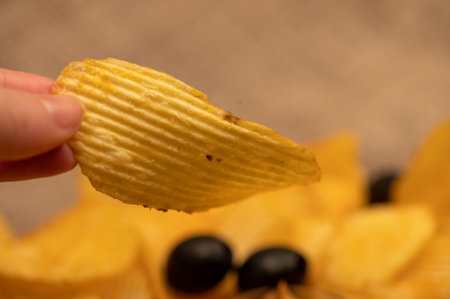 The girl's hand holds a slice of potato chips. Close up