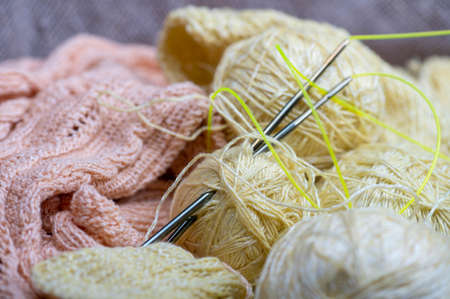 Knitting needles, skeins of yarn and knitted fabric, home needlework. Close-up, selective focusの写真素材