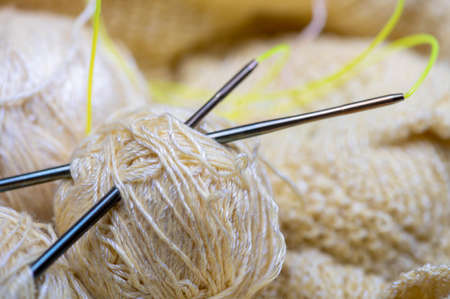 Knitting needles, skeins of yarn and knitted fabric, home needlework. Close-up, selective focusの写真素材