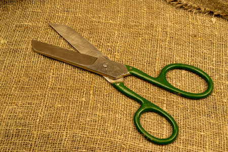 Large vintage scissors lie on rough homespun fabric. Close upの写真素材