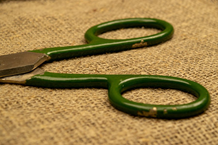 Large vintage scissors lie on rough homespun fabric. Close up
