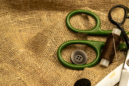Vintage sartorial scissors lying on rough fabric with threads and buttons