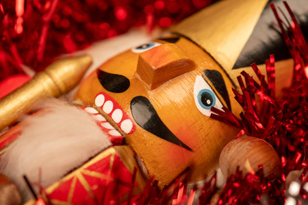 Wooden figure in the form of a soldier for chopping nuts surrounded by colored tinsel and hazelnuts in bulk. New year and Christmas. Close-up, selective focusの写真素材