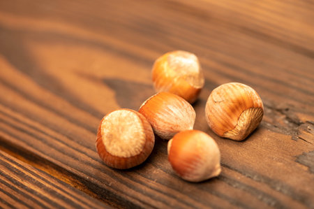 A few hazelnuts scattered on the wooden surface. Close-up, selective focus