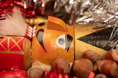 Wooden figure in the form of a soldier for chopping nuts surrounded by colored tinsel and hazelnuts in bulk. New year and Christmas. Close-up, selective focusの写真素材