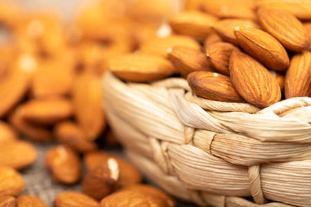 Almonds in a wicker basket and scattered on the table. Close-up, selective focusの写真素材