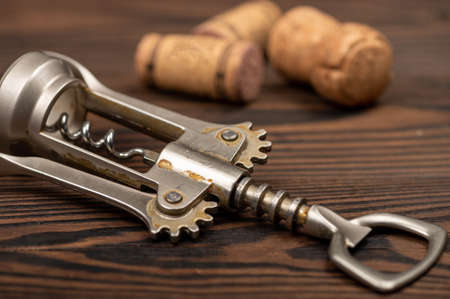Corkscrew and corks from wine bottles on a wooden table. Close-up, selective focus.の写真素材