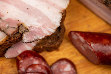 Sandwich with smoked brisket sliced on grain bread and homemade sausage on a wooden cutting board....