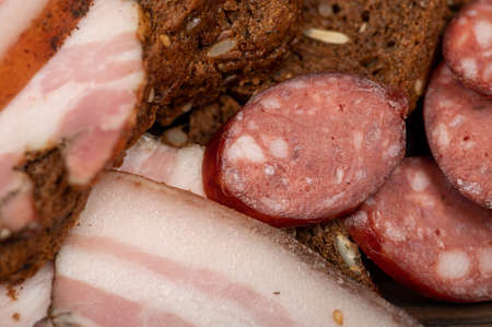 Sandwich with smoked brisket sliced on grain bread and homemade sausage on a wooden cutting board. Close-up, selective focus.の写真素材