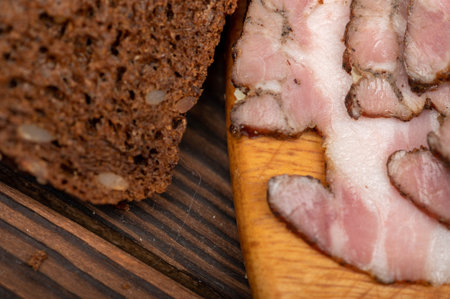 Smoked brisket sliced and grain bread on a wooden chopping board. Close-up, selective focus.