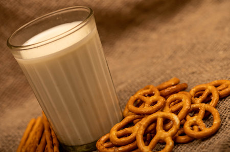 Salted breadsticks and salted pretzels in bulk and a glass of milk on the table. Close-up selective focus.の写真素材