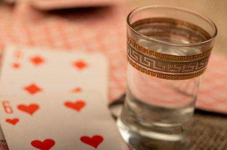 Playing cards and a glass of vodka on a table covered with coarse burlap. Close-up, selective focus.