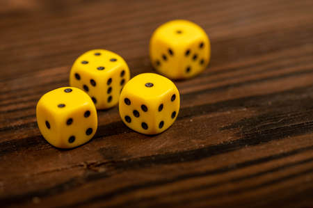 Yellow dice scattered on a wooden table. Close-up, selective focus. An indispensable attribute of board games.の写真素材