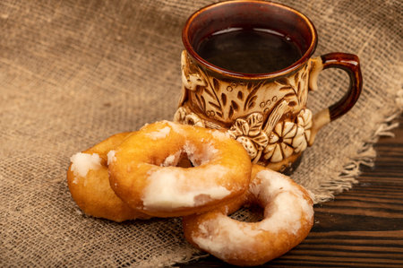 Fresh homemade donuts with powdered sugar and a earthenware mug of tea. Close-up Selective focus