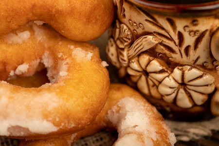 Fresh homemade donuts with powdered sugar and a earthenware mug of tea. Close-up Selective focus