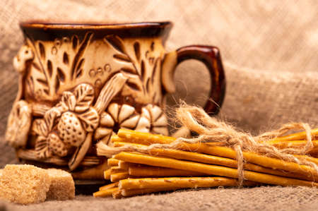 Breadsticks with salt tied with string and an earthenware mug for tea. Close-up Selective focusの写真素材