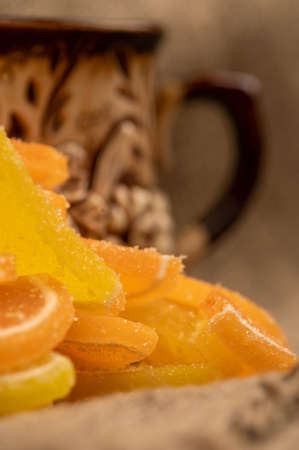 Multicolored shaped marmalade lemon slices and a ceramic tea mug, close-up, selective focusの写真素材