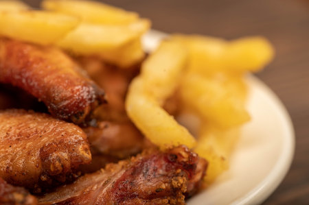 Fried chicken wings and French fries on a plate, close-up, selective focus