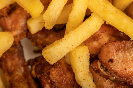 Fried chicken wings and French fries on a plate, close-up, selective focus