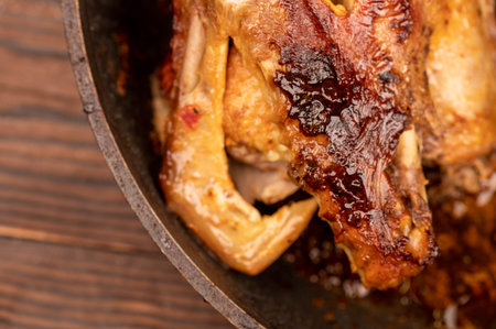 Pieces of roast duck with spices in a frying pan, close-up, selective focus