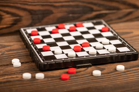 A board for playing checkers with chips on a wooden table, close-up, selective focusの写真素材