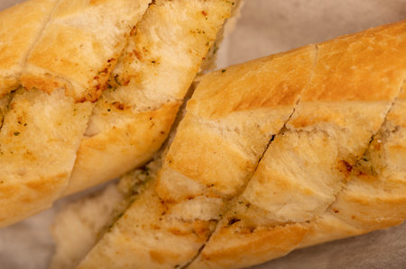 Baguette with garlic paste cut into pieces, close-up, selective focus
