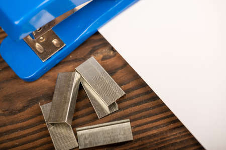 Office stapler, stapler staples and white paper on the table, close-up, selective focusの写真素材