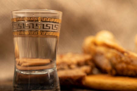 A small fried fish on a wooden board, pieces of bread and a glass of vodka, close-up, selective focusの写真素材