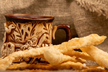Fried bread sticks with salt and a ceramic mug, close-up, selective focusの写真素材