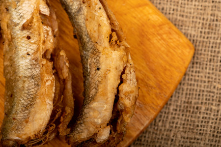 Small fried fish on a wooden board, close-up, selective focusの写真素材