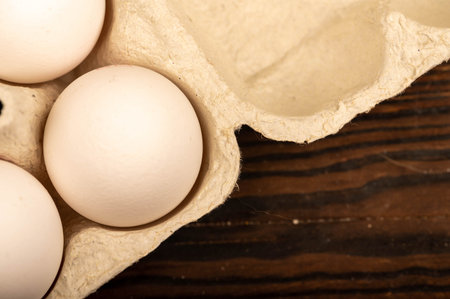 White chicken eggs in a tray made of white cardboard, close-up selective focus