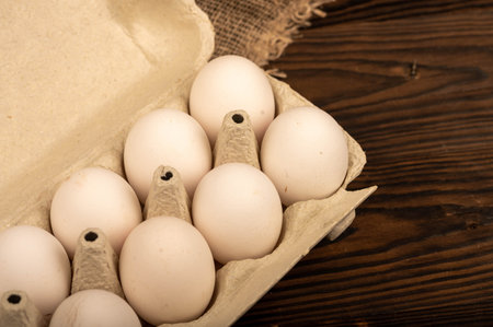 White chicken eggs in a tray made of white cardboard, close-up selective focus