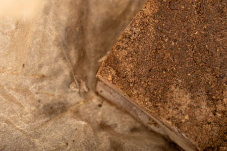 A piece of homemade bacon with pepper on white oiled paper, close-up, selective focusの写真素材