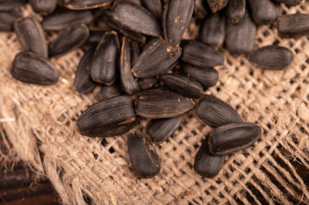 Fried black sunflower seeds scattered on the table, close-up, selective focus