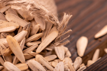 White sunflower seeds scattered on the background of coarse burlap, close-up selective focusの写真素材
