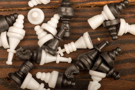 Black and white chess pieces scattered on a wooden table, close-up, selective focusの写真素材