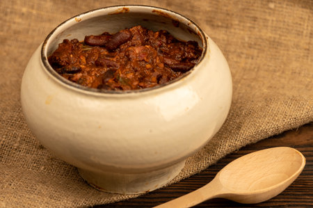 Stewed beans with meat in a small pot. A traditional rustic dish. Close up, selective focusの写真素材