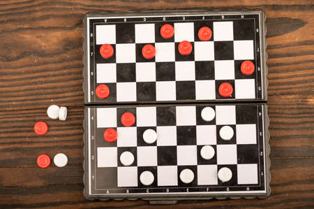 A board for playing checkers with chips on a wooden table, close-up, selective focusの写真素材
