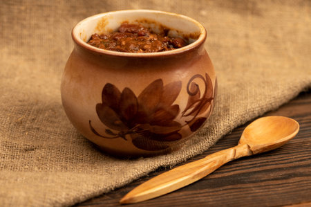 Stewed beans with meat in a small pot. A traditional rustic dish. Close up, selective focus