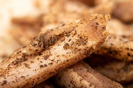 thinly sliced homemade lard with pepper on white oiled paper, close-up, selective focusの写真素材