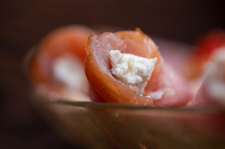 A roll of dried meat and soft cheese on a glass dish on the table. Festive table setting.