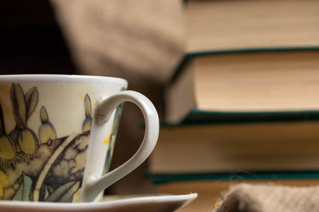 A cup of strong tea on a saucer and a stack of books on the tableの写真素材