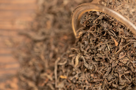 Large-leaf black tea in a glass and scattered on the table. Close-up of the surface texture
