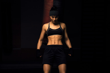 Girl boxer in black bandages stands leaning on a boxing bagの写真素材