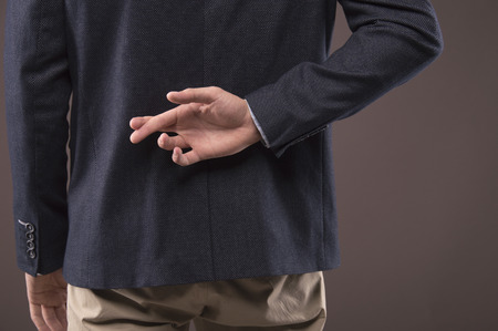 Businessman fingers crossed behind his backの写真素材