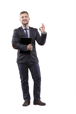 Businessman standing in suit with laptop in his hands and showing sign of okの写真素材