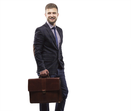 Young man smiling in a suit with a briefcase in his handsの写真素材