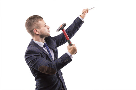 Young man beats hammer on the chisel with a smileの写真素材