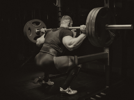 Professional athlete makes squats with a bar in the gymの写真素材