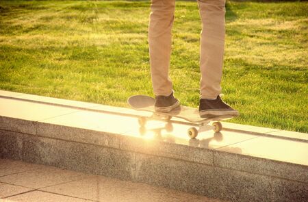 Desperate skateboarder performs dangerous movement on the skateboard at sunsetの写真素材